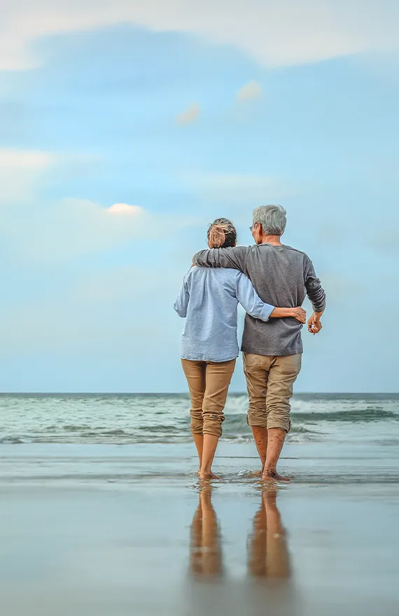 couple walking with their arms around each other at the beach annuities for retirement