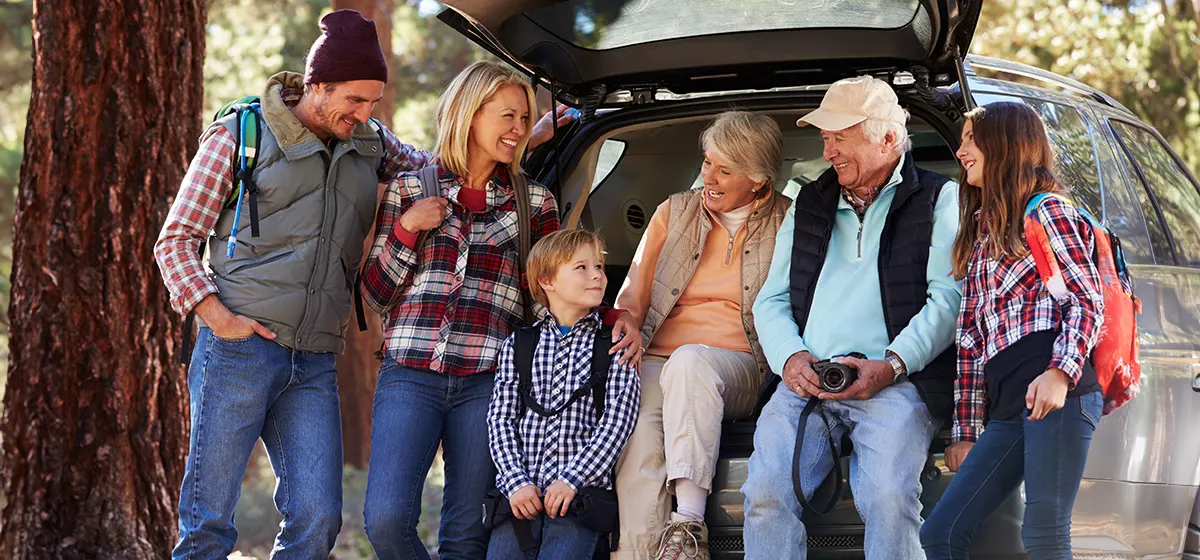 multigenerational family standing outside their car getting ready to go on a hike life insurance in retirement